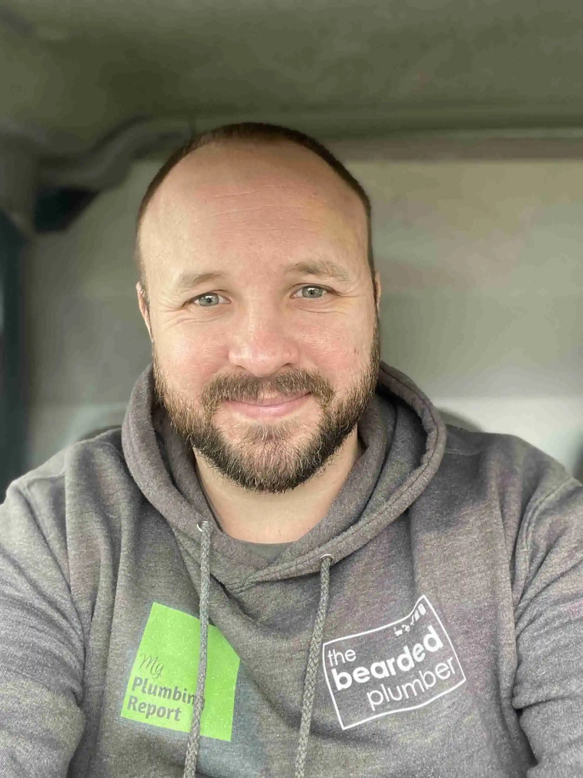 Stu Clark in his van, wearing a plumbing company hoodie